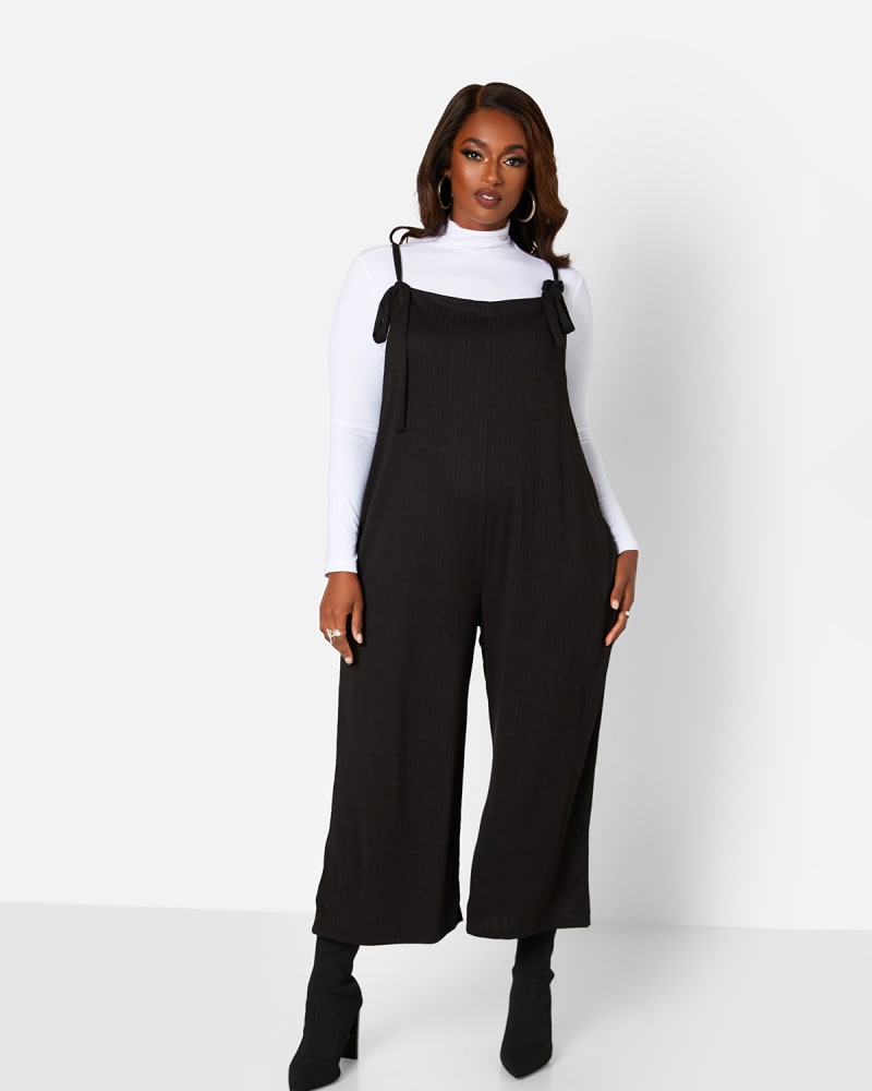 Front of a model wearing a size 2X Lets Chill Ribbed Tie Strap Oversized Jumpsuit W. Pockets in Black by Rebdolls. | dia_product_style_image_id:325396